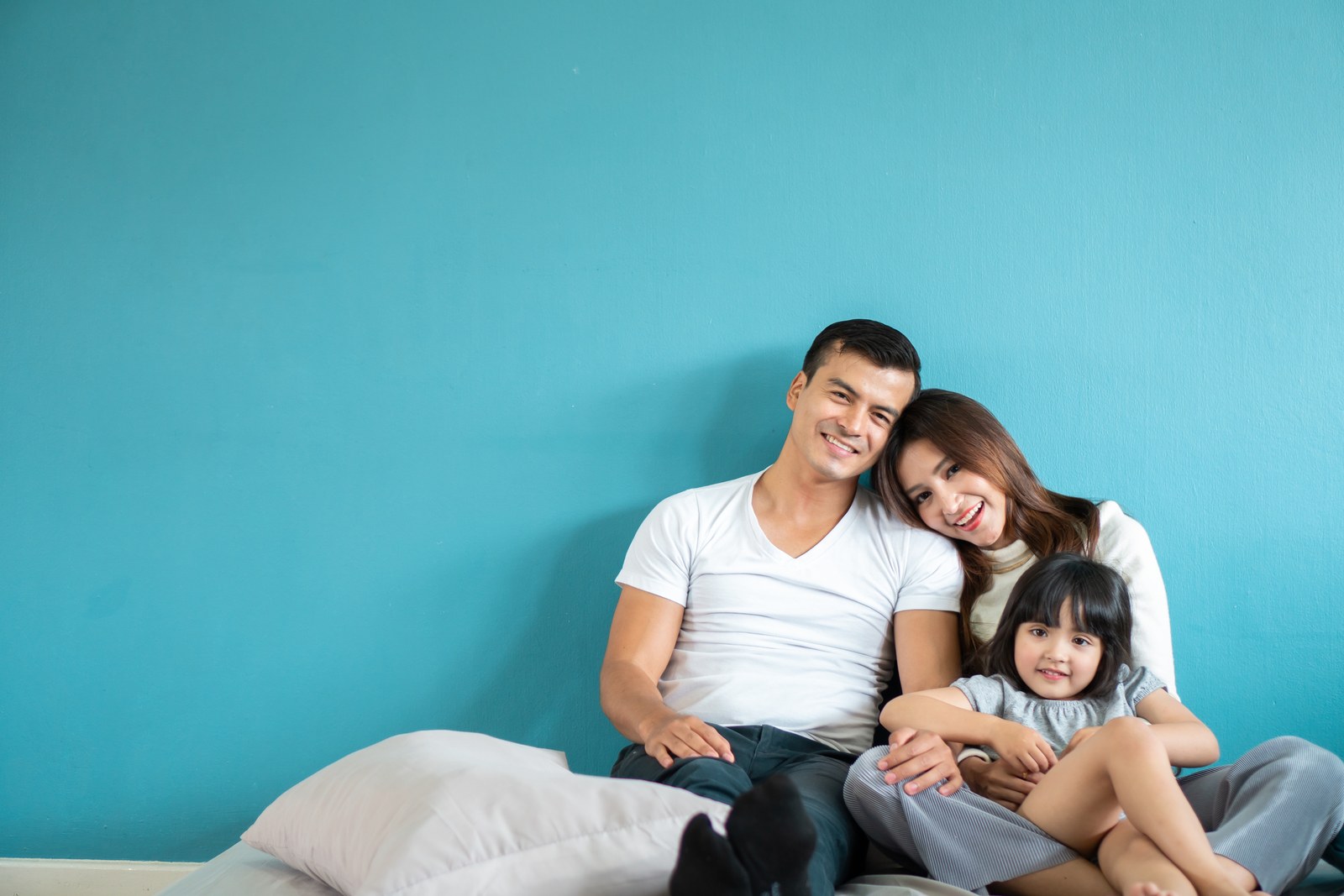 Family of three sitting together on a bed
